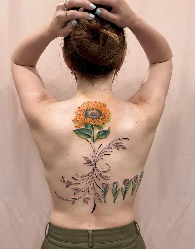 Tatuaggio colorato con girasole, rami sottili e tulipani sulla schiena