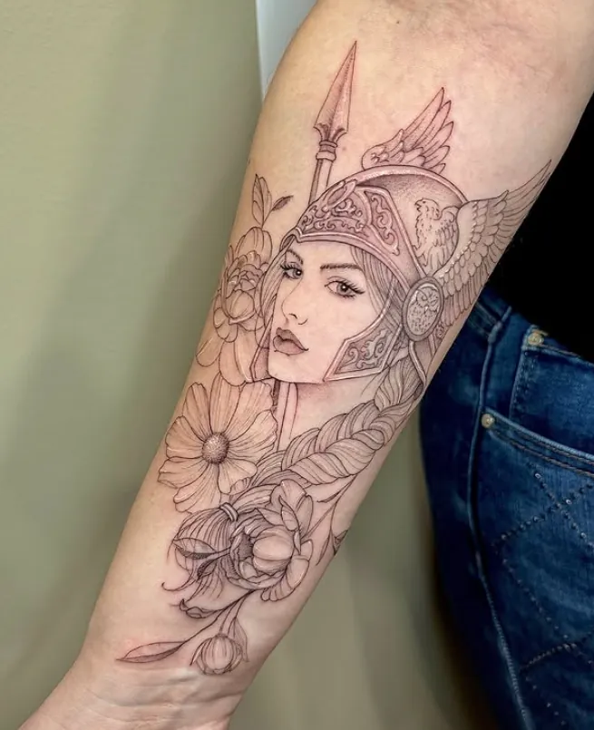 Tatuaggio fine line di una guerriera con elmo alato, peonie e margherita sull'avambraccio